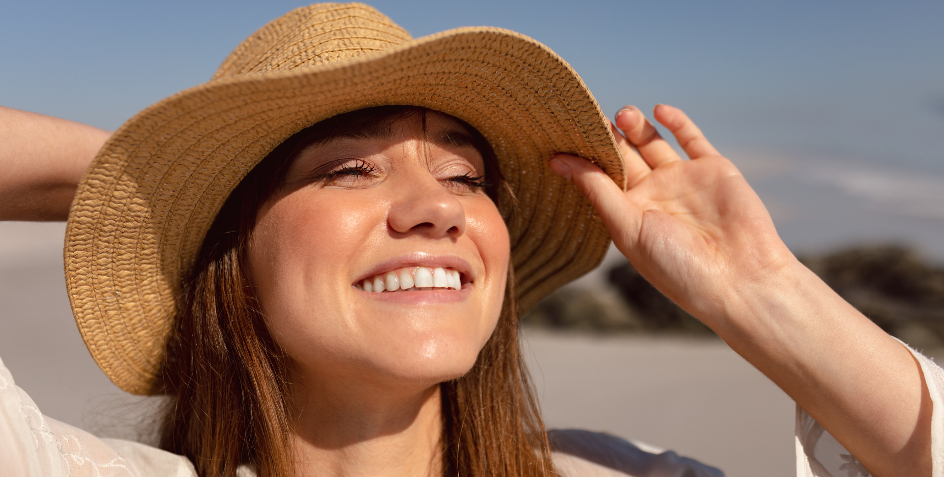 Mulher de chapéu sorrindo durante exposição solar