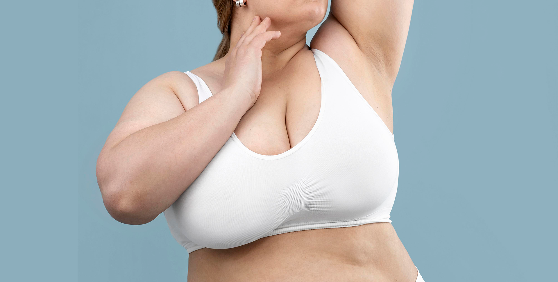 Mulher de top com mamas pesadas, caso que pode passar por uma mamoplastia redutora.